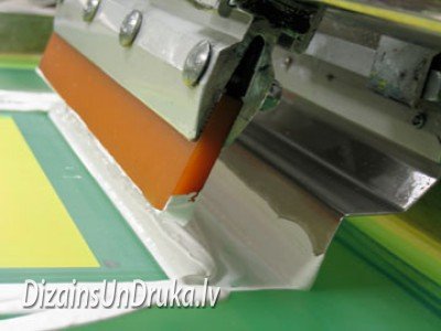 Процесс трафаретной печати: ракель наносит белую краску через сетку